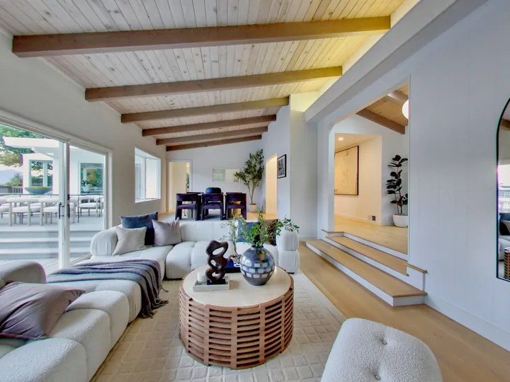 Living room with exposed ceiling beams and steps up to the dining area