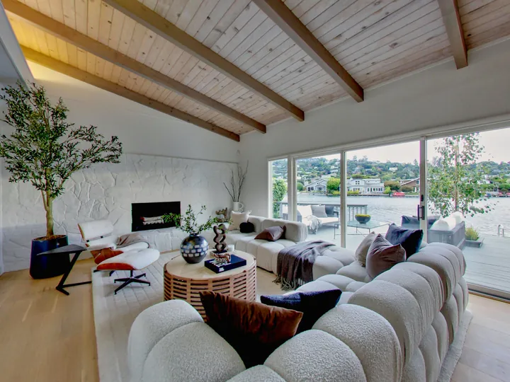 Living room with a beamed ceiling, fireplace and sliding doors to the water