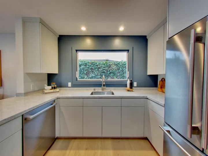 U-shaped kitchen with a window over the sink and a blue accent wall