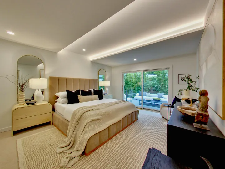 Bedroom with a cove-lit ceiling and sliding doors to a patio
