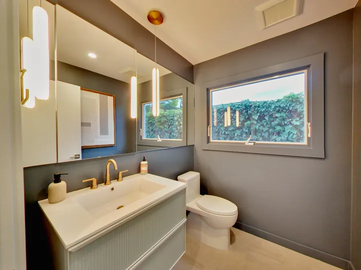 Bathroom with brass fixtures, a fluted vanity and a gray accent wall