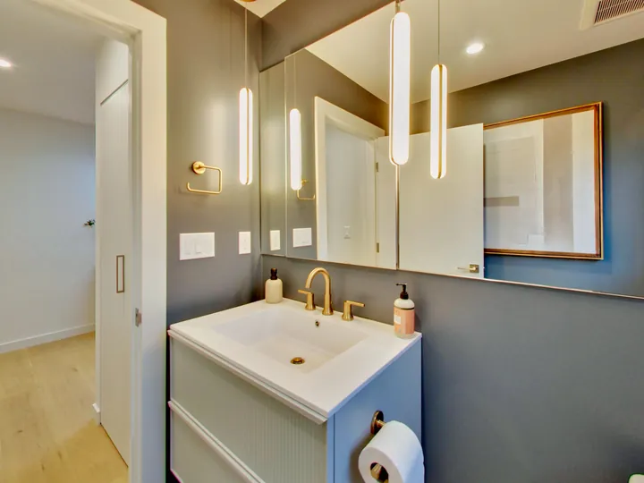 Bathroom vanity with brass fixtures and pendant lights
